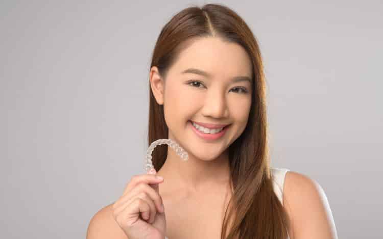 Smiling female patient showing clear Invisalign aligners